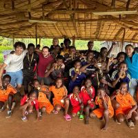 1 - Foto di gruppo volontari con bambini e medaglie sotto il tukul